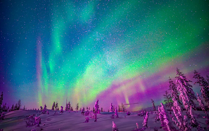Snowmobiles under Northern Lights in Rovaniemi, Finland.