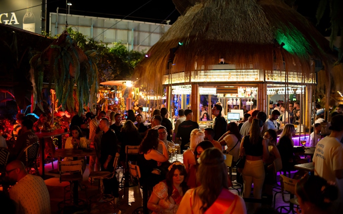Crowded bar scene at Baloo Ibiza with people socializing under colorful lights.