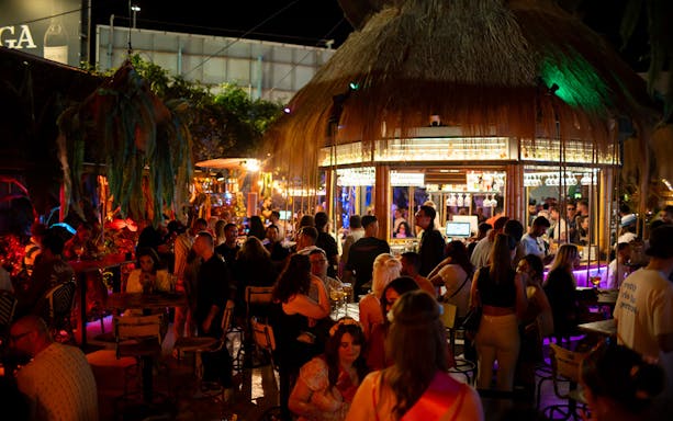 Crowded bar scene at Baloo Ibiza with people socializing under colorful lights.