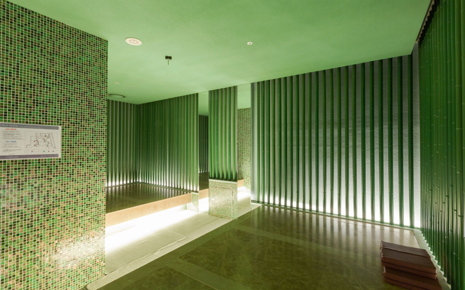 Spa Land Centum City Busan interior with green tiled walls and seating area.