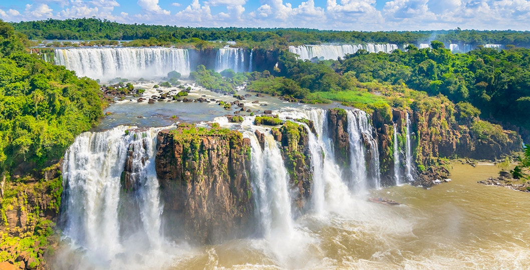 Iguazu Falls cascading between Brazil and Argentina, lush greenery surrounding.