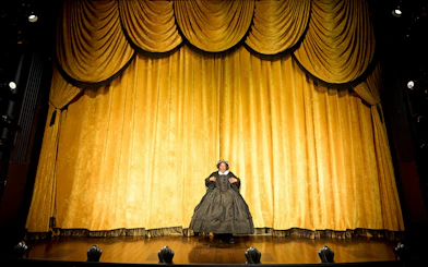Performer on stage in front of gold curtain during "Oh Mary" show, West End.