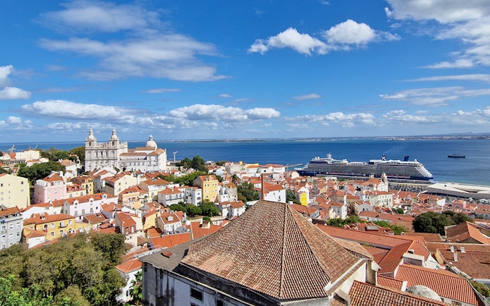 Lisbon cityscape with St. George's Castle Church tower and cruise ship in the harbor.
