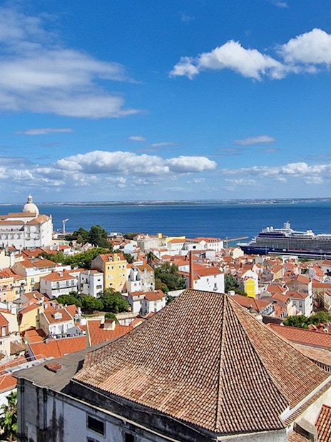 Lisbon cityscape with St. George's Castle Church tower and cruise ship in the harbor.