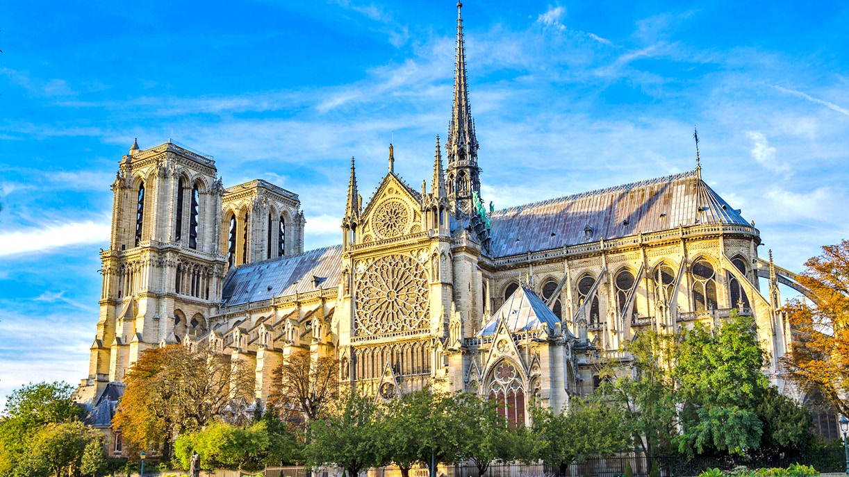 Notre-Dame Cathedral in Paris with detailed facade and spire under a blue sky.