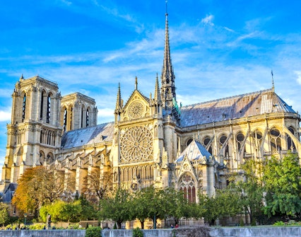 Notre-Dame Cathedral in Paris with detailed facade and spire under a blue sky.