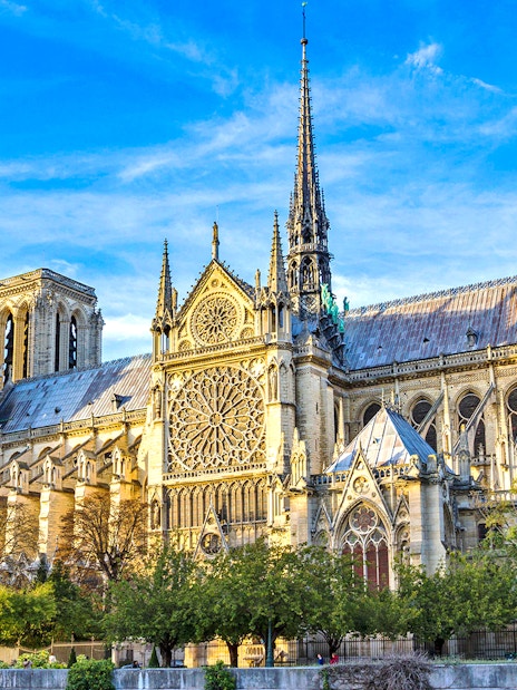 Notre-Dame Cathedral in Paris with detailed facade and spire under a blue sky.