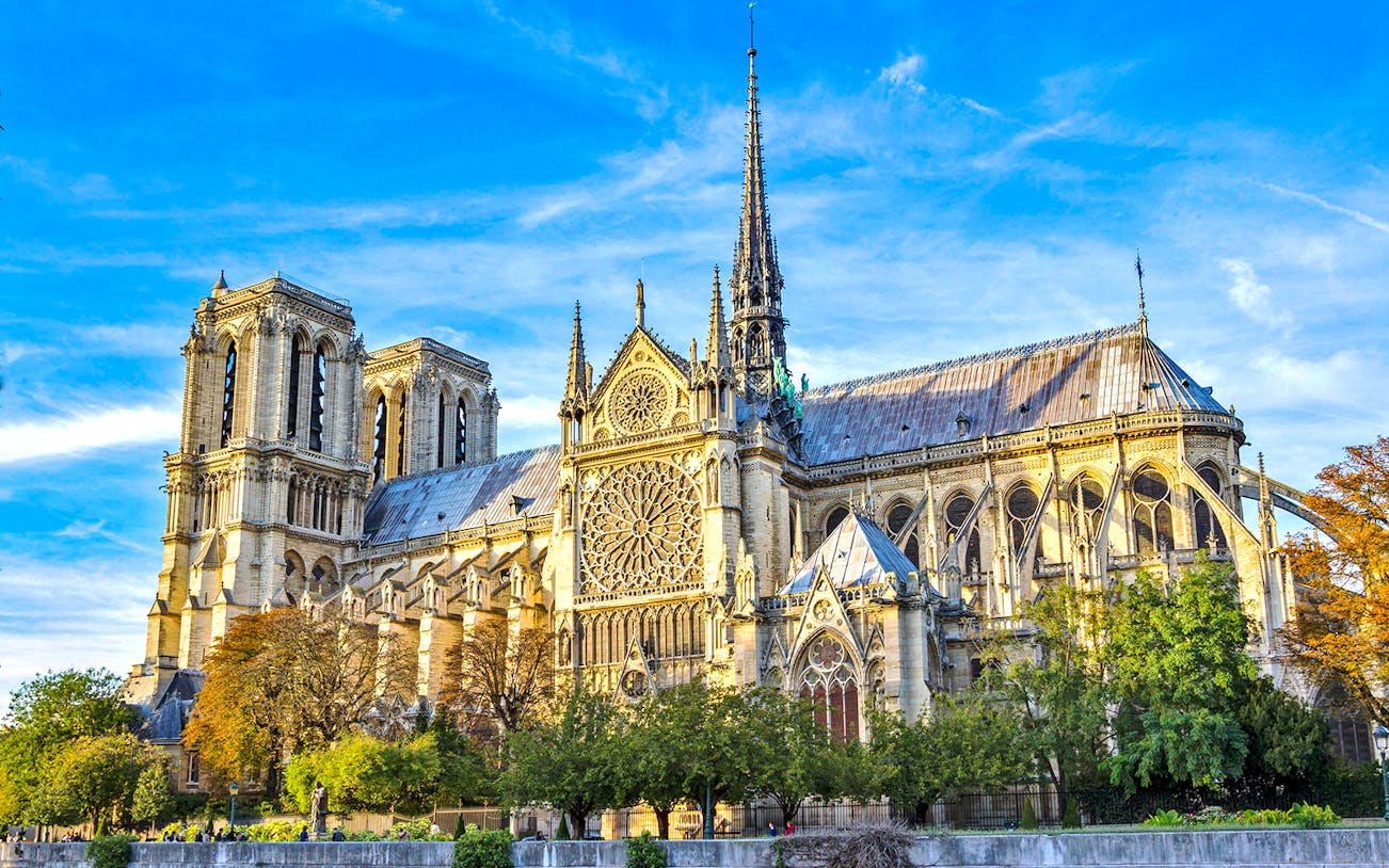 Notre-Dame Cathedral in Paris with detailed facade and spire under a blue sky.