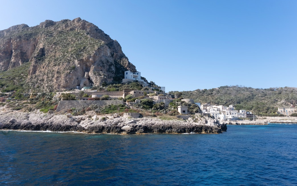 Levanzo coastline with rocky cliffs and white buildings near Sicily.