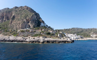 Levanzo coastline with rocky cliffs and white buildings near Sicily.
