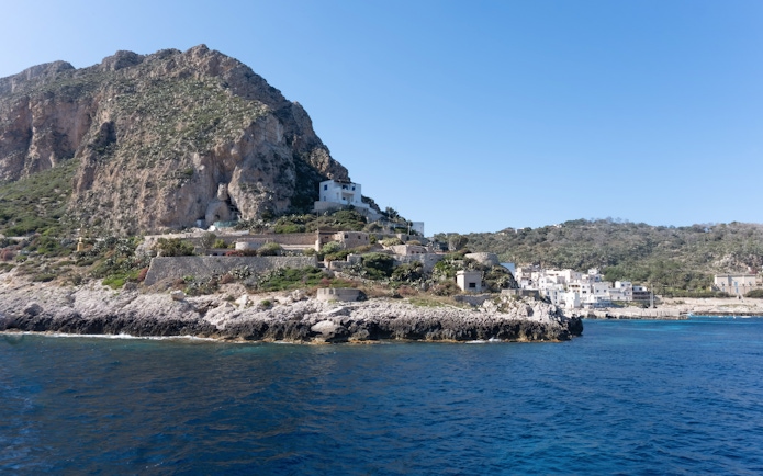 Levanzo coastline with rocky cliffs and white buildings near Sicily.