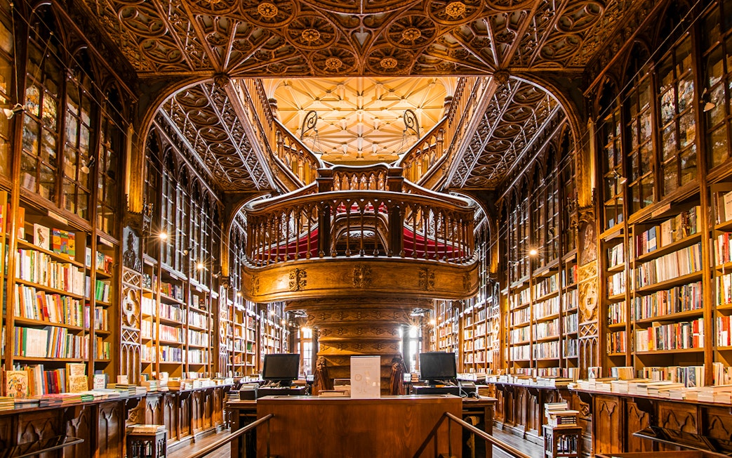 Livraria Lello interior with ornate wooden staircase and bookshelves, Porto, Portugal.