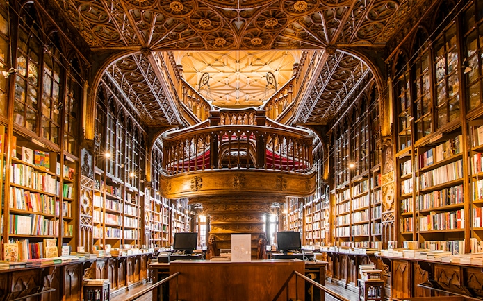 Livraria Lello interior with ornate wooden staircase and bookshelves, Porto, Portugal.