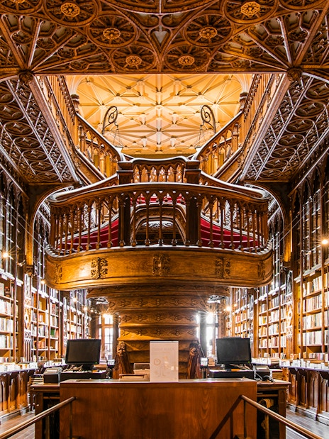 Livraria Lello interior with ornate wooden staircase and bookshelves, Porto, Portugal.