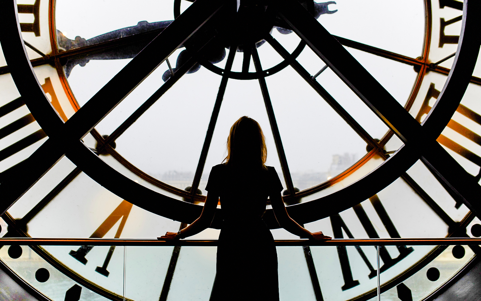 Woman standing inside the Orsay Museum clocktower, Paris, overlooking the city.