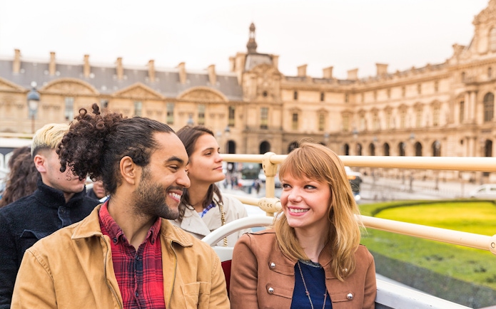 Tourists enjoying a Paris hop-on hop-off bus tour near Place Vendôme.