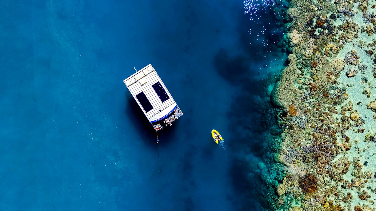 Glass bottom boat near coral reef at Airlie Beach, with a kayak nearby.