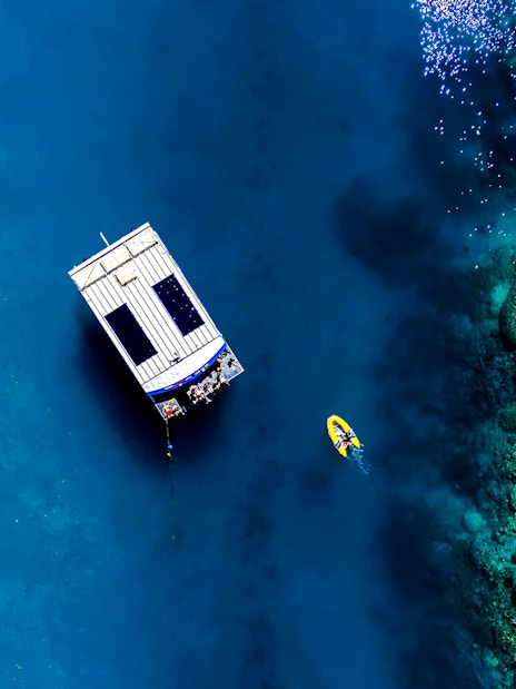 Glass bottom boat near coral reef at Airlie Beach, with a kayak nearby.