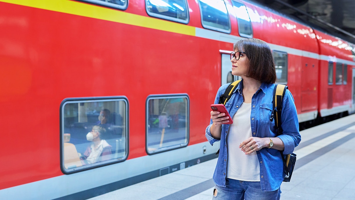 Woman waiting on railway platform inside station with luggage.