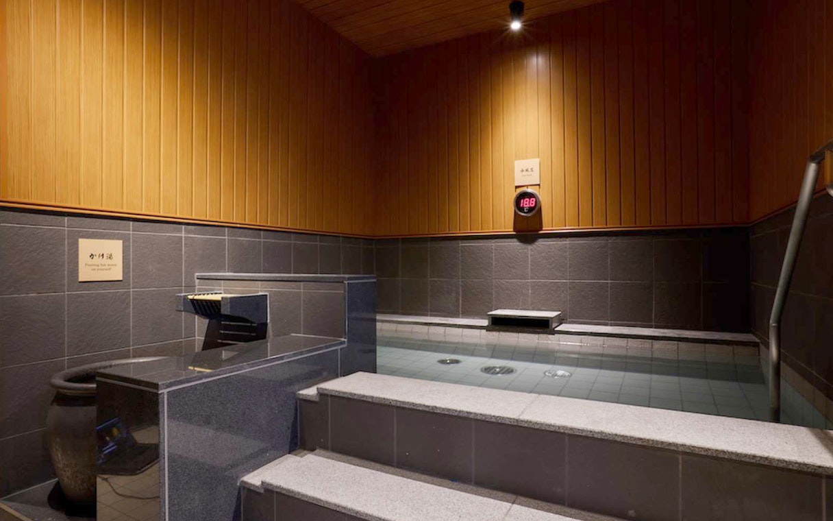 Indoor hot spring bath at Solaniwa Onsen, Japan, with wooden and stone decor.