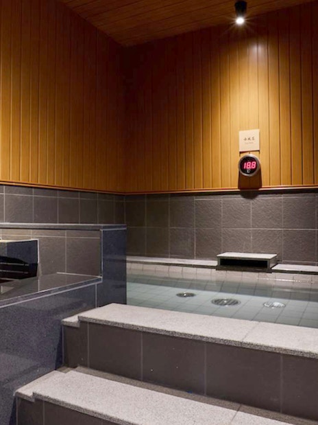 Indoor hot spring bath at Solaniwa Onsen, Japan, with wooden and stone decor.