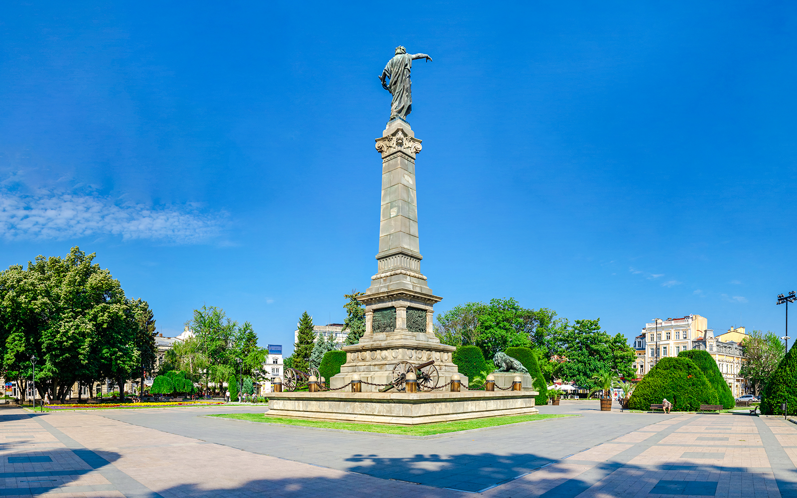 Freedom Monument in Ruse, Bulgaria, surrounded by trees and city buildings.