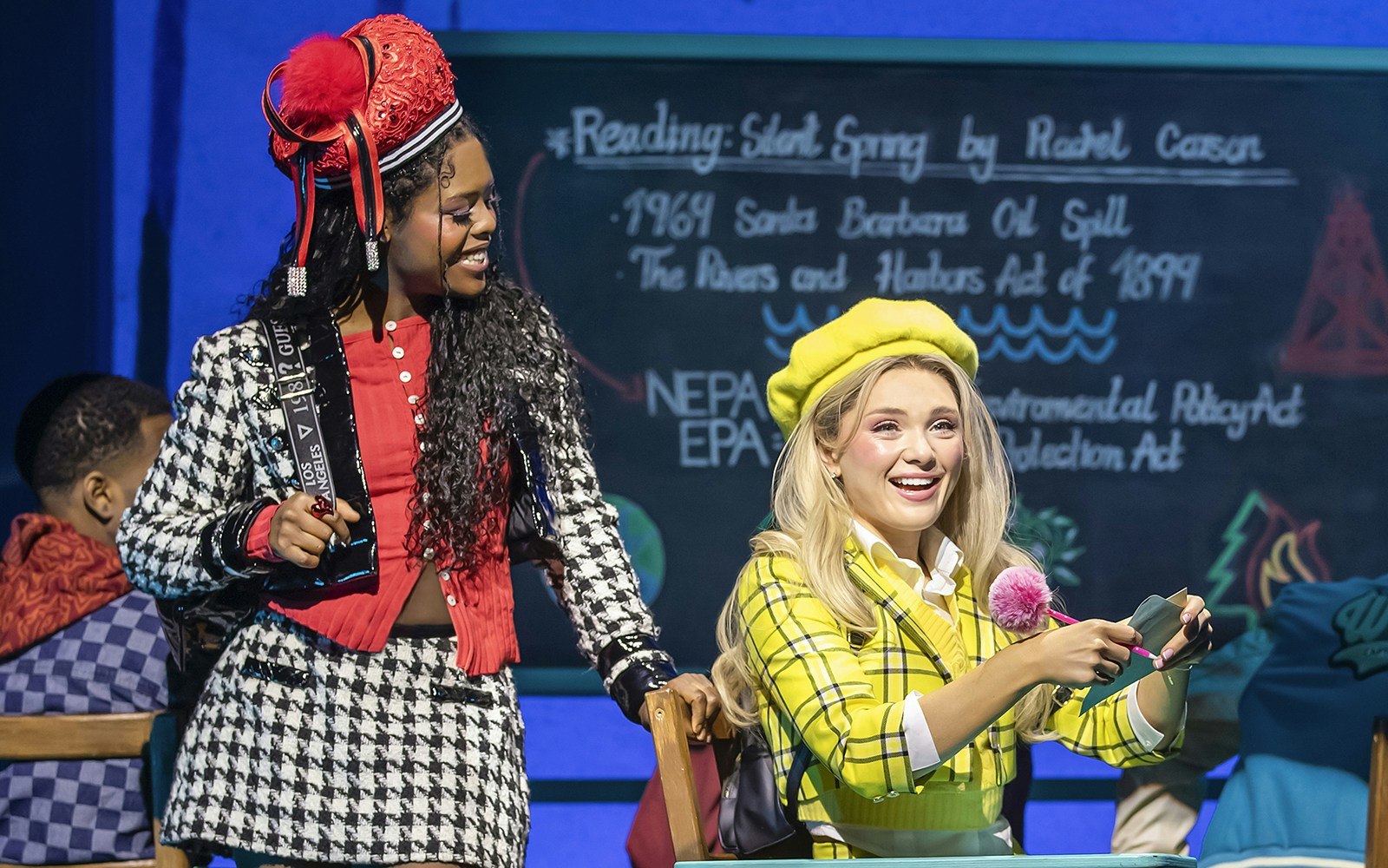 Two actors in colorful costumes performing a scene from Clueless The Musical.