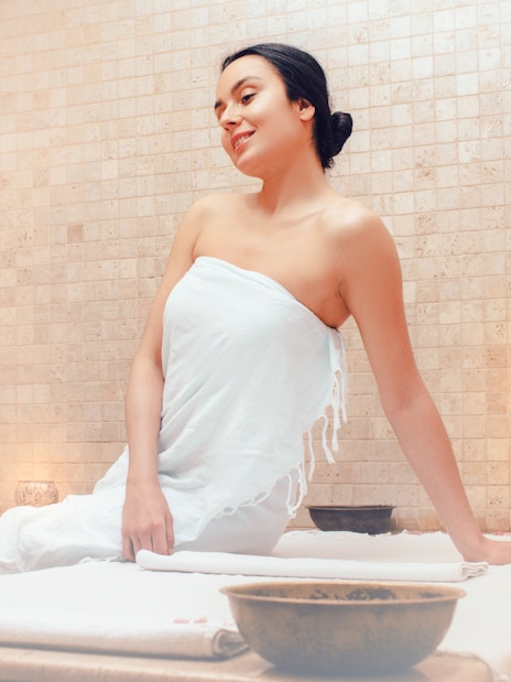 Woman relaxing in a Turkish hammam sauna, wrapped in a towel.