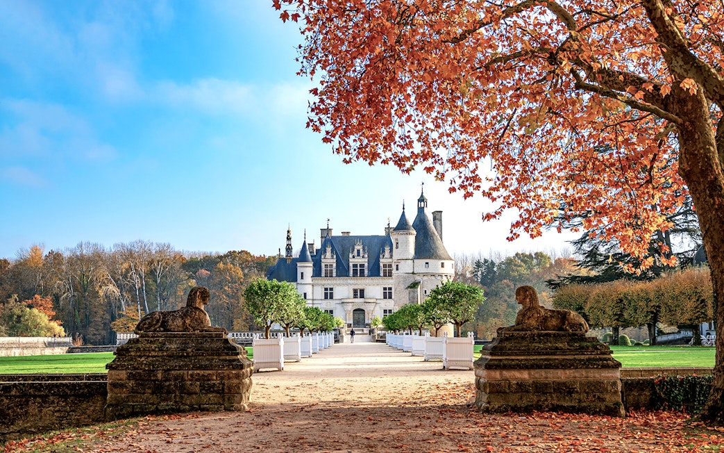 Château de Chenonceau in autumn with red leaves and stone sculptures, Loire Valley, France.