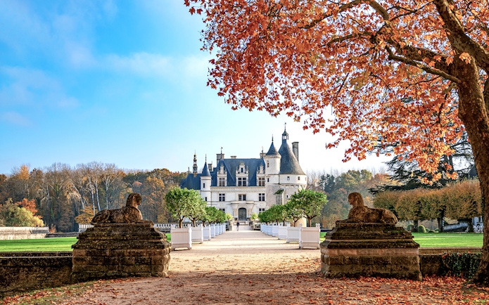 Château de Chenonceau in autumn with red leaves and stone sculptures, Loire Valley, France.