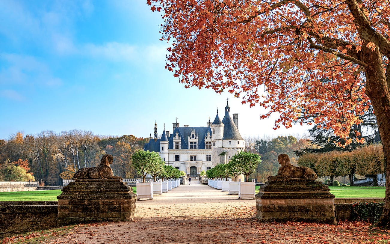 Château de Chenonceau in autumn with red leaves and stone sculptures, Loire Valley, France.