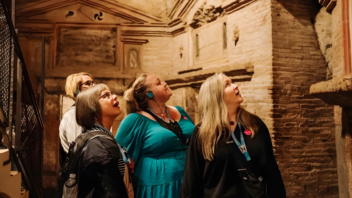 Tour group with audio guide in underground catacombs, Rome