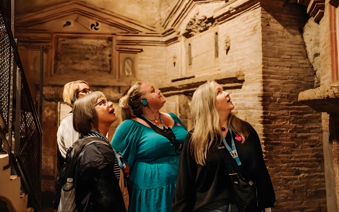 Tour group with audio guides exploring underground catacombs in Rome.