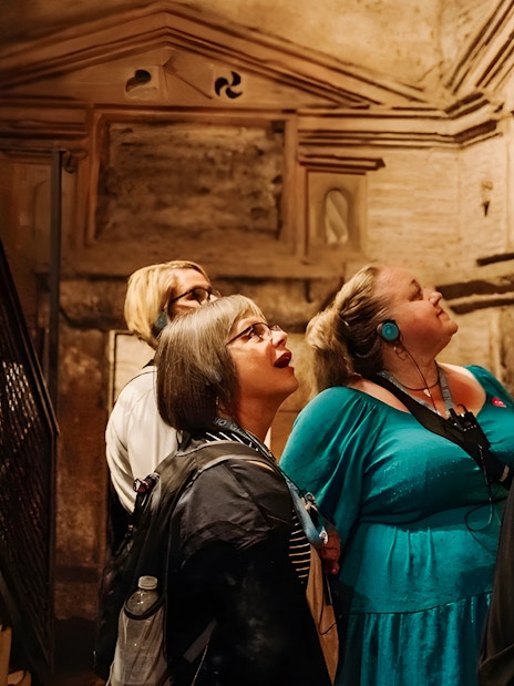 Tour group with audio guides exploring underground catacombs in Rome.