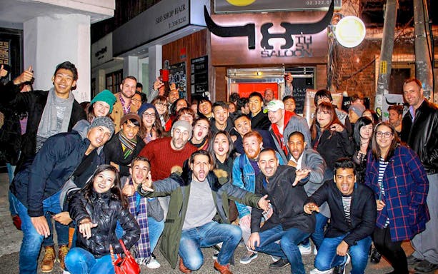 Group of people enjoying a Seoul pub crawl outside a bar.
