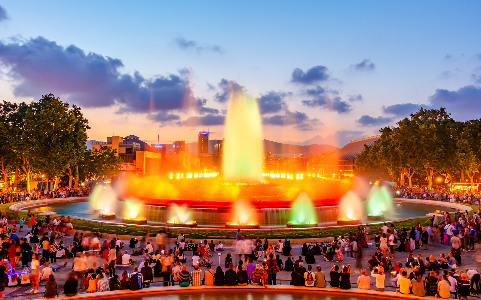 Magic fountain show at Montjuic hill, Barcelona, with colorful lights and crowd.