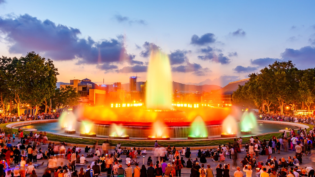 Magic fountain show at Montjuic hill, Barcelona, with colorful lights and crowd.