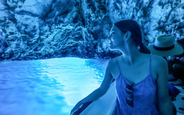 Woman admiring the blue light inside the Blue Cave during a boat tour from Split.