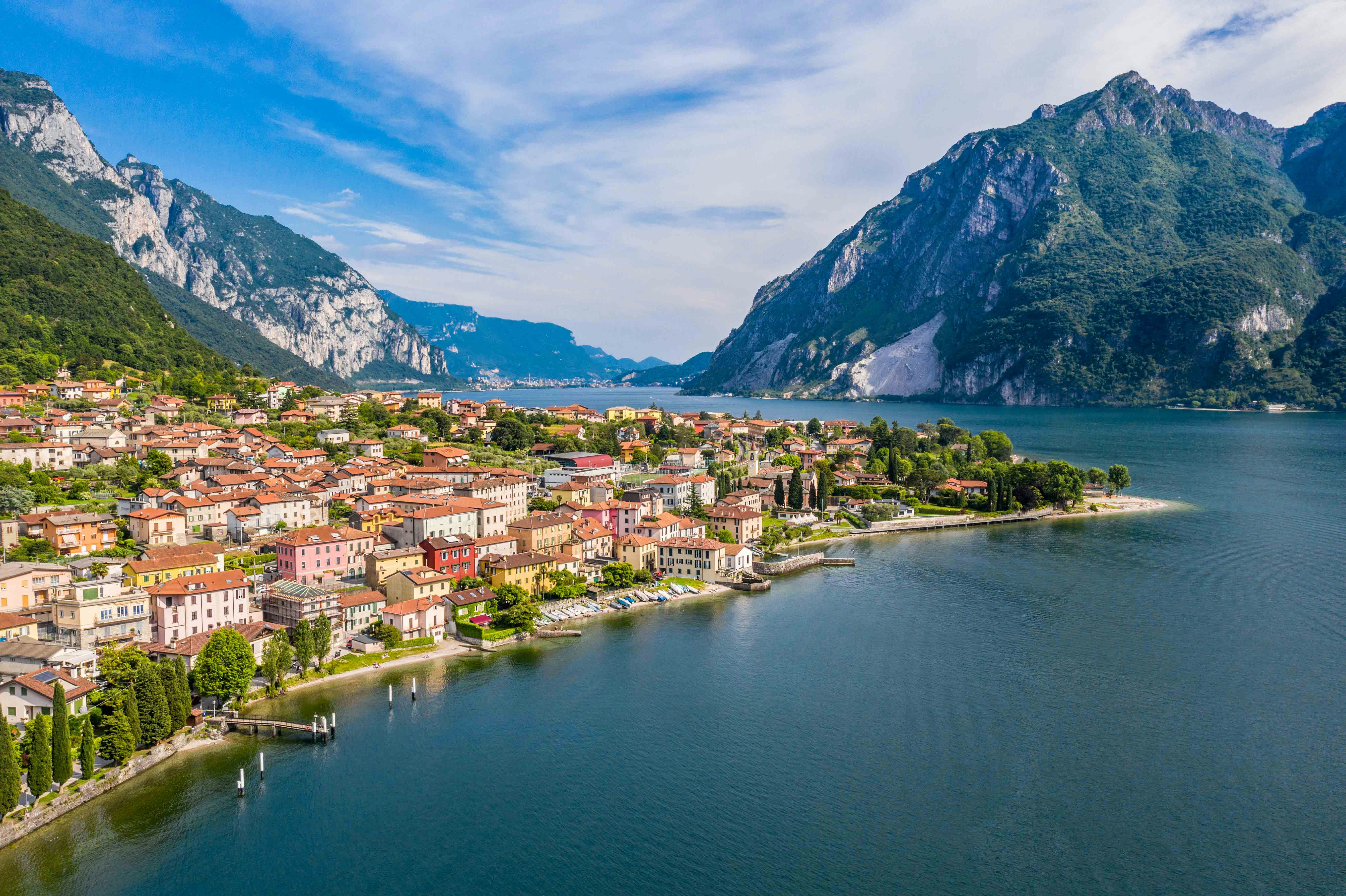 Aerial view of colorful buildings along Lake Como with mountains in the background, Milan in December.