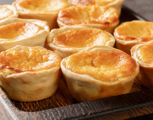 Queijadas de Sintra, sweet cheese tarts with cinnamon, on a wooden tray.
