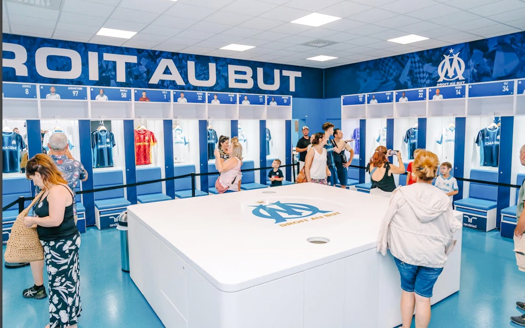 Visitors exploring the locker room during a Velodrome stadium tour in Marseille.