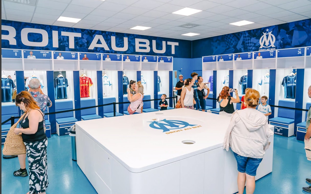 Visitors exploring the locker room during a Velodrome stadium tour in Marseille.