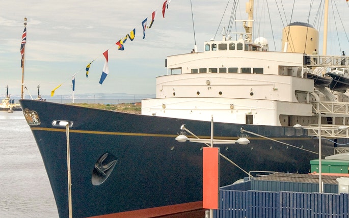 Royal Yacht Britannia docked with flags displayed.