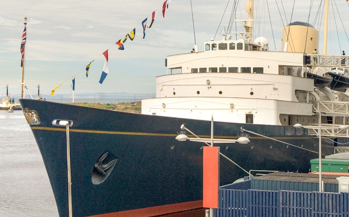 Royal Yacht Britannia docked with flags displayed.