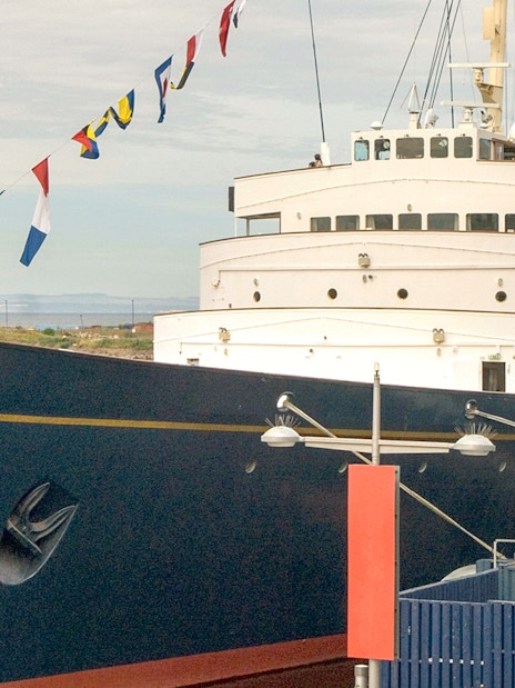 Royal Yacht Britannia docked with flags displayed.