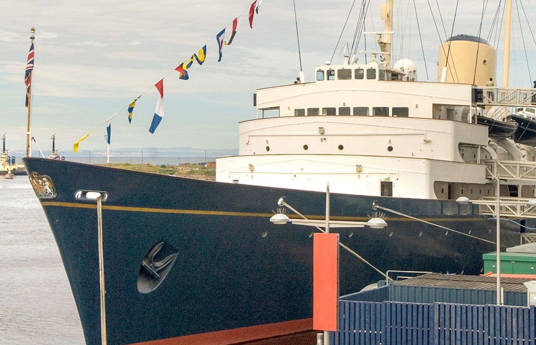 Royal Yacht Britannia docked with flags displayed.
