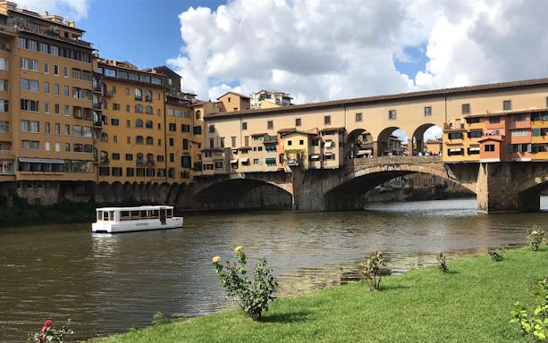 Ponte Vecchio over Arno River with tour boat, Florence walking tour.