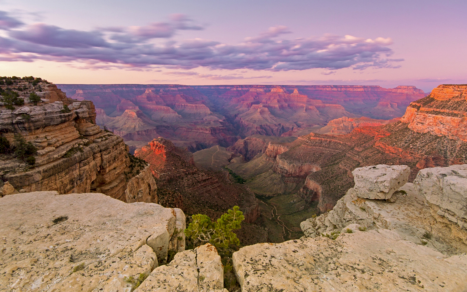 Grand Canyon at sunset with layered rock formations and expansive canyon view.