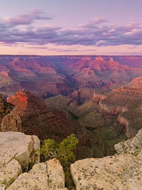Grand Canyon at sunset with layered rock formations and expansive canyon view.