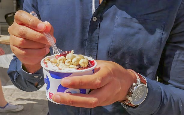 Man enjoying yogurt with toppings during Athens Old Town Food Experience.